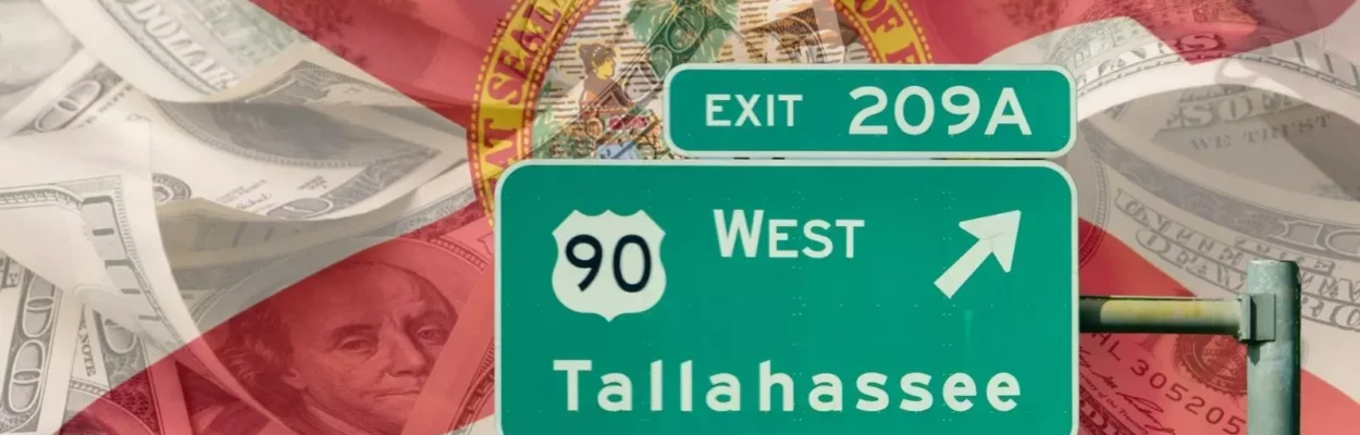 A green exit sign to Tallahassee is in front of a background with one hundred dollar bills and a transparent Florida flag.