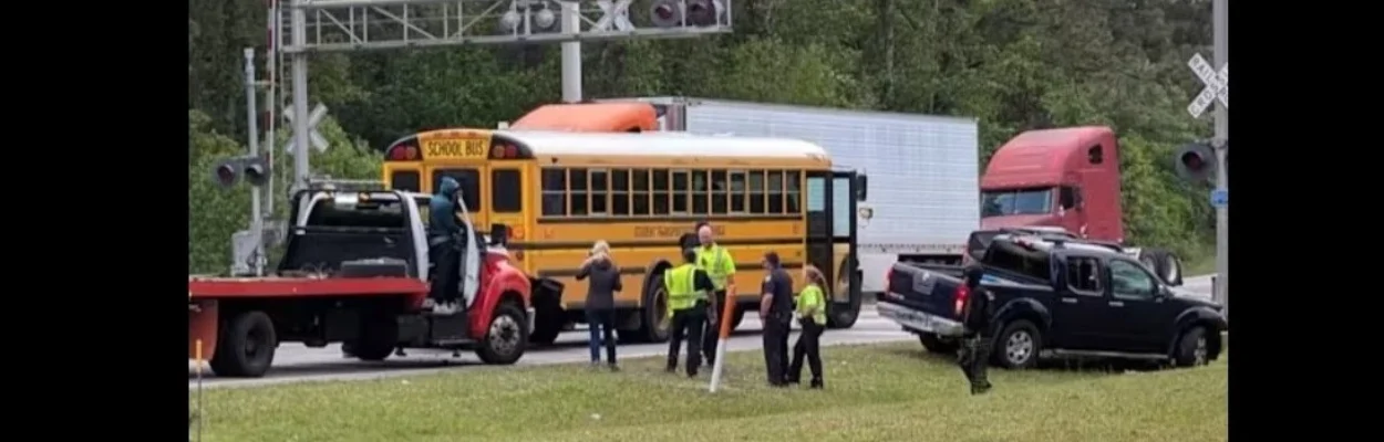 A school bus is stopped at railroad tracks where it was in a crash with a truck.
