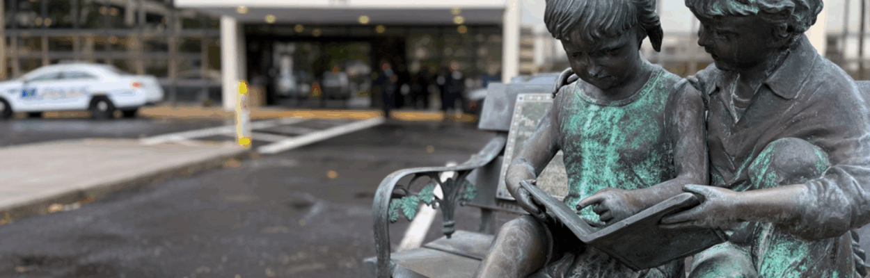 A statue of children reading in front of DCPS headquarters.