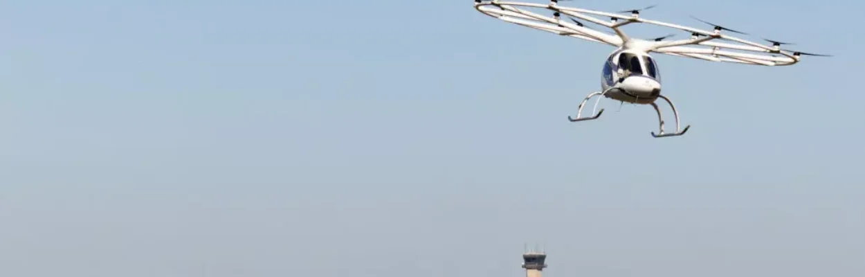 An air taxicab flies over an airport terminal.