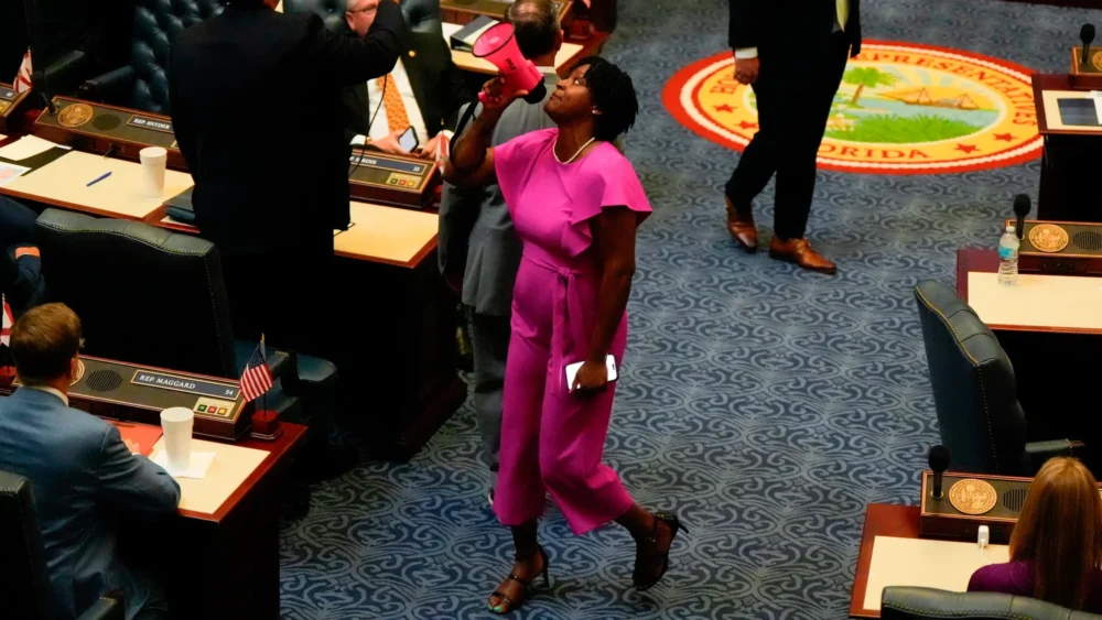 Angie Nixon walks while talking into a bright pink megaphone
