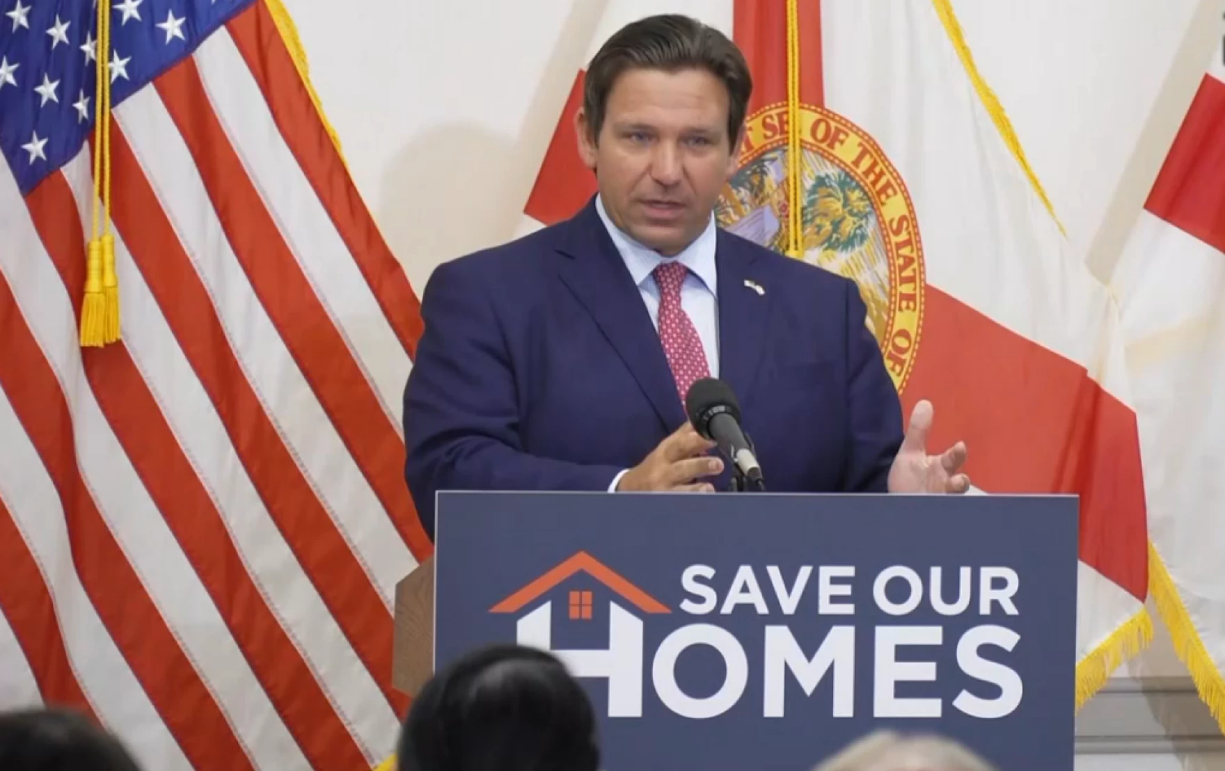 Gov. Ron DeSantis standing at a microphone as he calls for eliminating most property taxes.