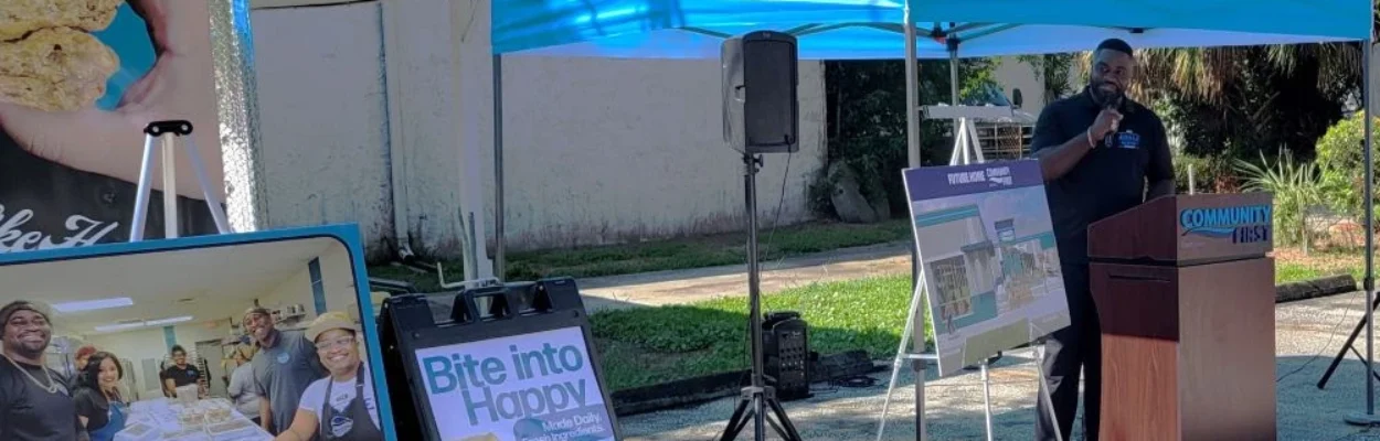 Arble Baking Co. co-founder Alonza Anderson stands under a tent talking about the new credit union office and sandwich bakery.
