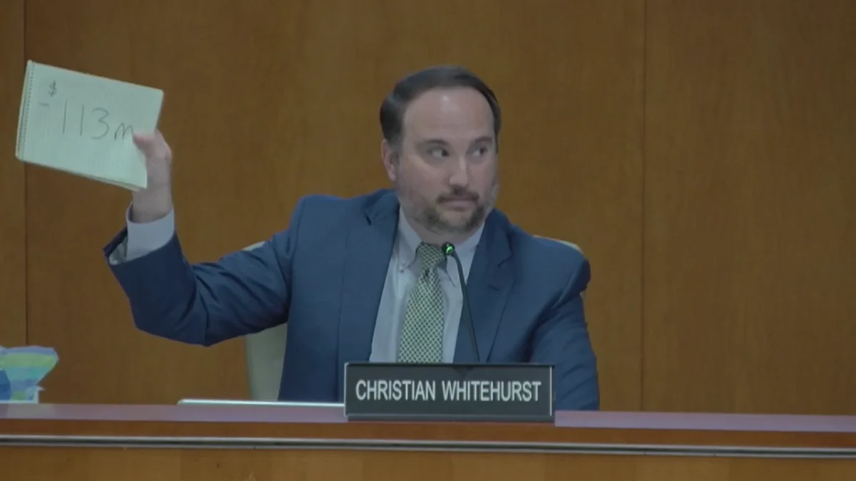 St. Johns County Commissioner Christian Whitehurst holds up a sign reading "$113" in reference to the estimated $113 million in tax revenue the county could lose by 2029 if voters approved property tax cuts.