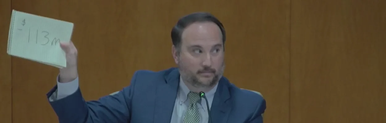 St. Johns County Commissioner Christian Whitehurst holds up a sign reading "$113" in reference to the estimated $113 million in tax revenue the county could lose by 2029 if voters approved property tax cuts.