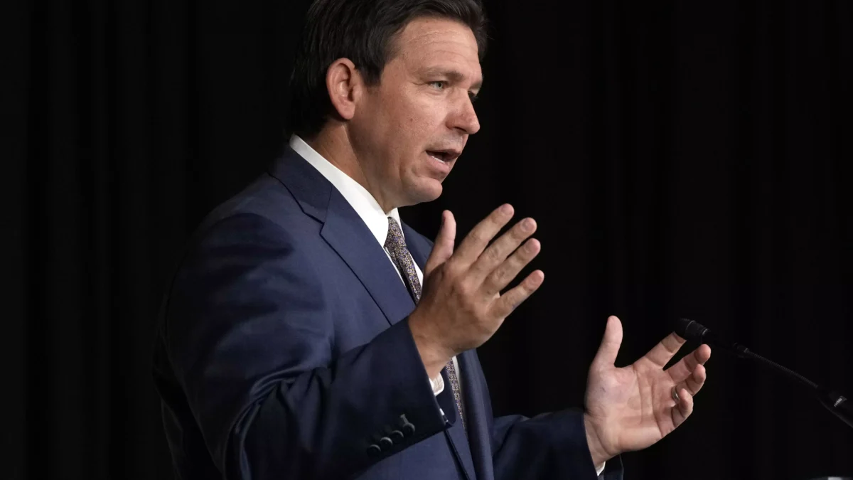 Man in blue suit and tie stands on stage with hands in the air