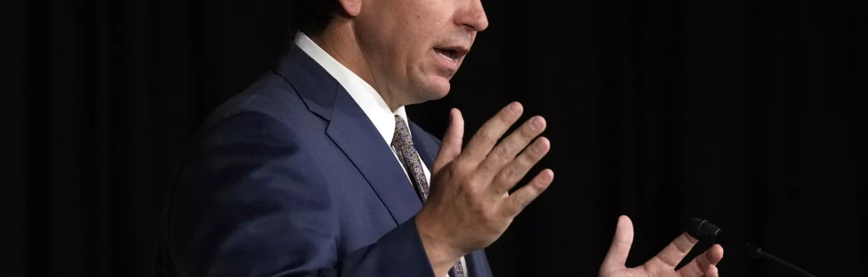 Man in blue suit and tie stands on stage with hands in the air