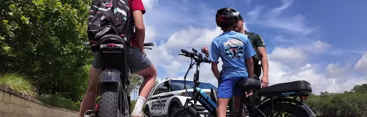 Two e-bike riders talk with a police officer.