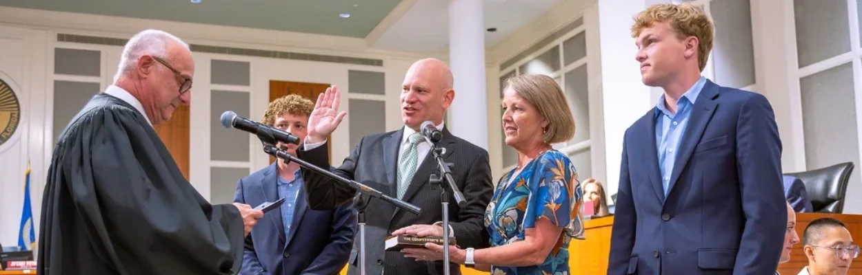 Nick Howland raises his hand as he is sworn in as City Council