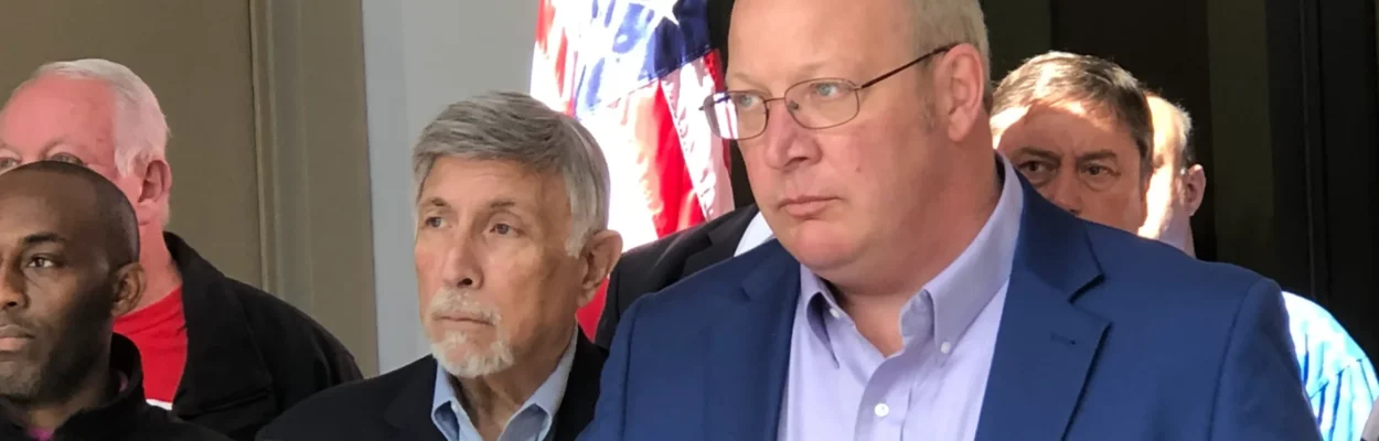 Former City Council President Scott Wilson stands in front of microphones at a news conference.