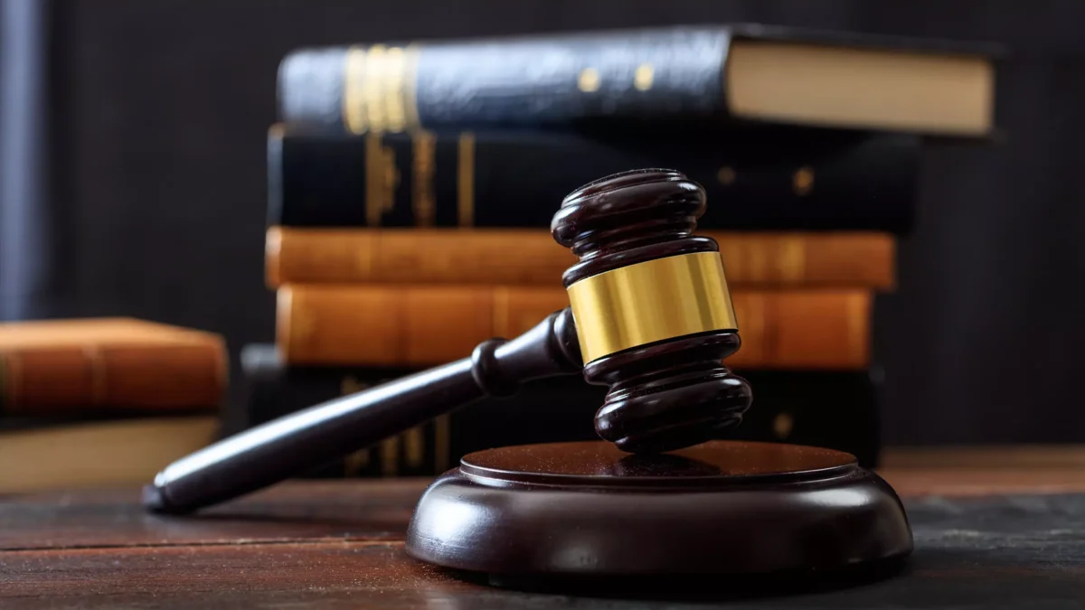 Gavel on a wooden desk, with law books in the background. The image represents fraud in the COVID-19 Payment Protection Program