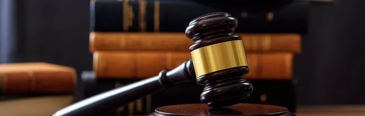 Gavel on a wooden desk, with law books in the background