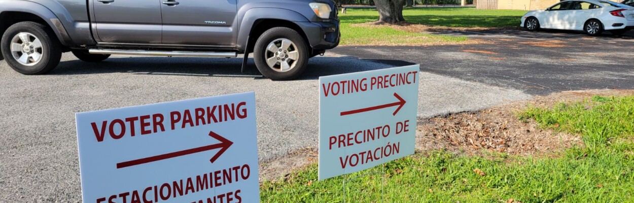 On a day with modest voter turnout, a truck drives into a voting precinct with signs pointing to the polling location.