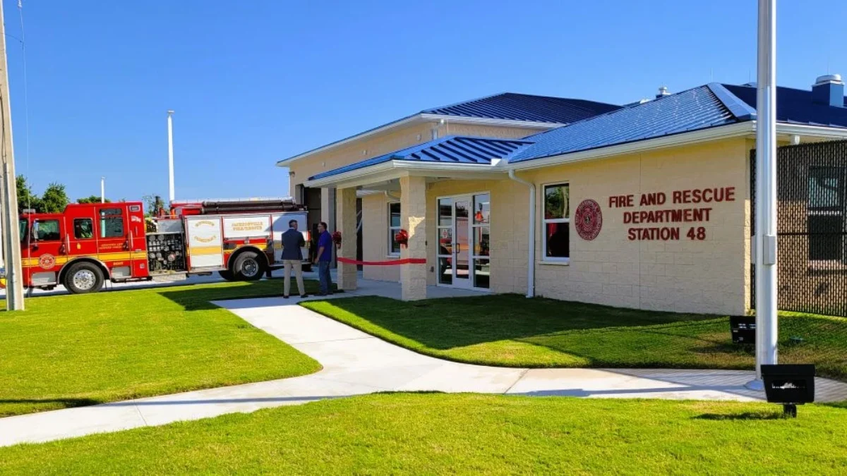 A fire truck sits outside the new Fire Station 48. Two men are standing outside talking.