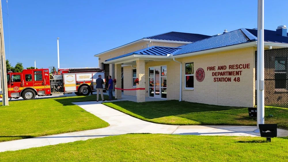 A fire truck sits outside the new Fire Station 48. Two men are standing outside talking.