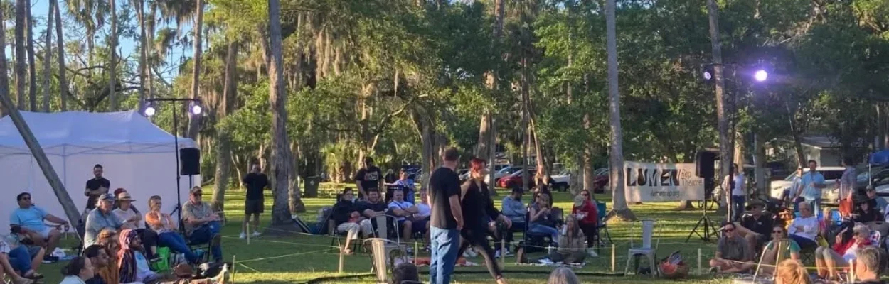 Spectators sit in the park for Theatre in the Park