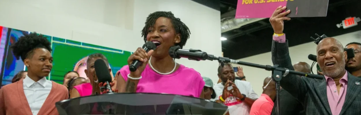 Angie Nixon speaks at podium surrounded by supporters