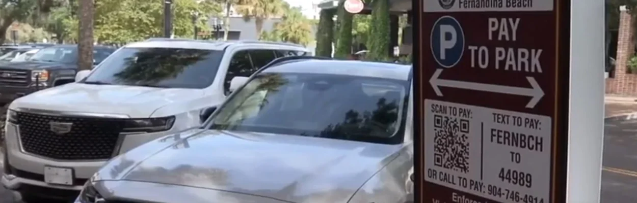 A sign next to cars in downtown Fernandina Beach explains how to pay for parking.