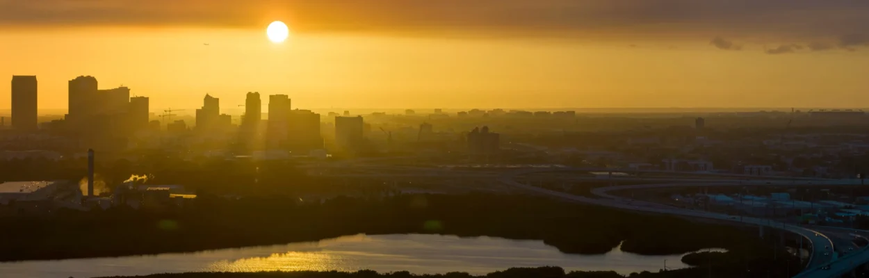 Aerial view of downtown Tampa at sunset during the summer. Dark silhouette of high skyscraper office buildings in modern american midtown.