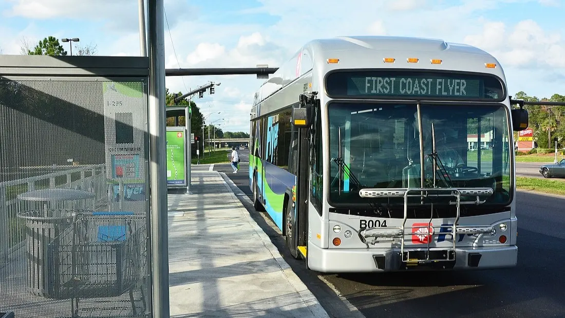 A JTA First Coast Flyer bus pulled over to the curb at a bus stop.
