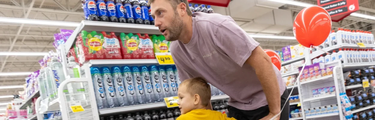 Jaguars punter Logan Cooke bends over a shopping cart holding two children during a hunger event.