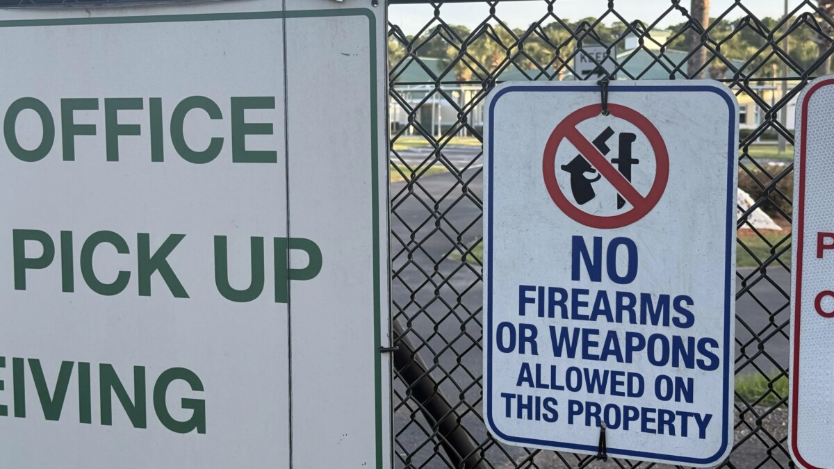 sign on a school fence with the words "No firearms" and a gun crossed out on it