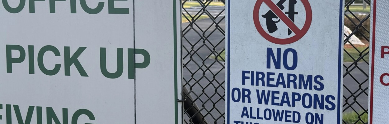 sign on a school fence with the words "No firearms" and a gun crossed out on it