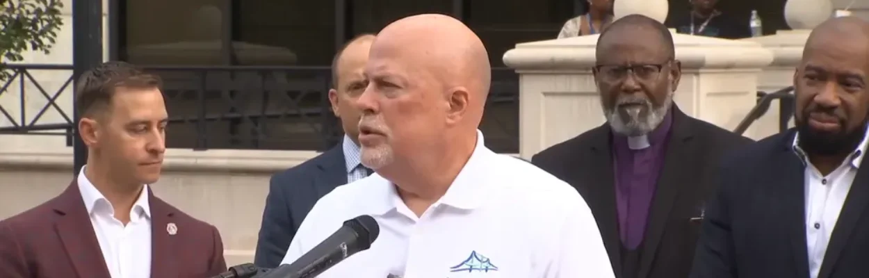A man in a white golf shirt speaks at a lectern about a new rental tool.