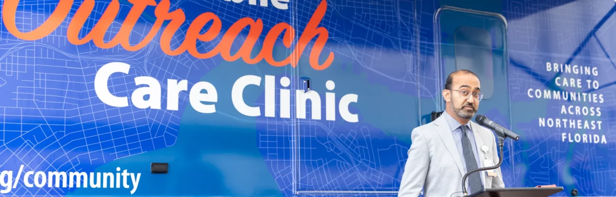 UF Health Jacksonville Chief Medical Officer Dr. Chirag Patel standing next to a blue vehicle labeled "Mobile Outreach Care Clinic."