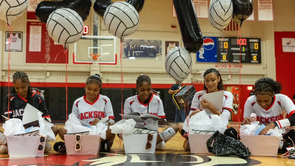 Andrew Jackson volleyball players open gift boxes.