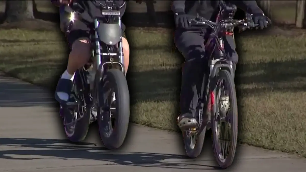 Two people ride e-bikes on a path.