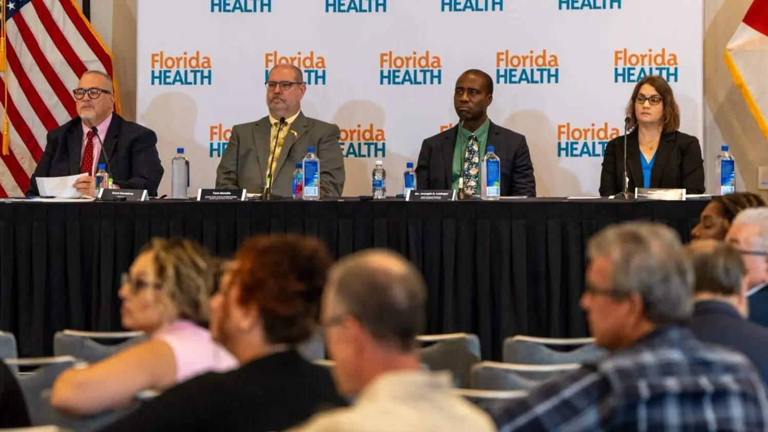 4 people on a panel listen to speakers about a proposal to remove four vaccine requirements for schools.
